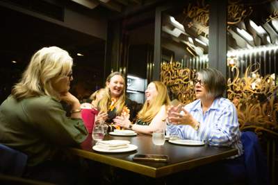A group of people are smiling and chatting while seated around a table.