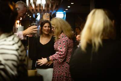 Two women are deep in conversation in a room full of other women mingling at a Change Makers lunch event.
