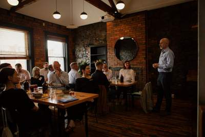 A large group of marketing managers and CMOs meet for lunch and sit around long communal tables.